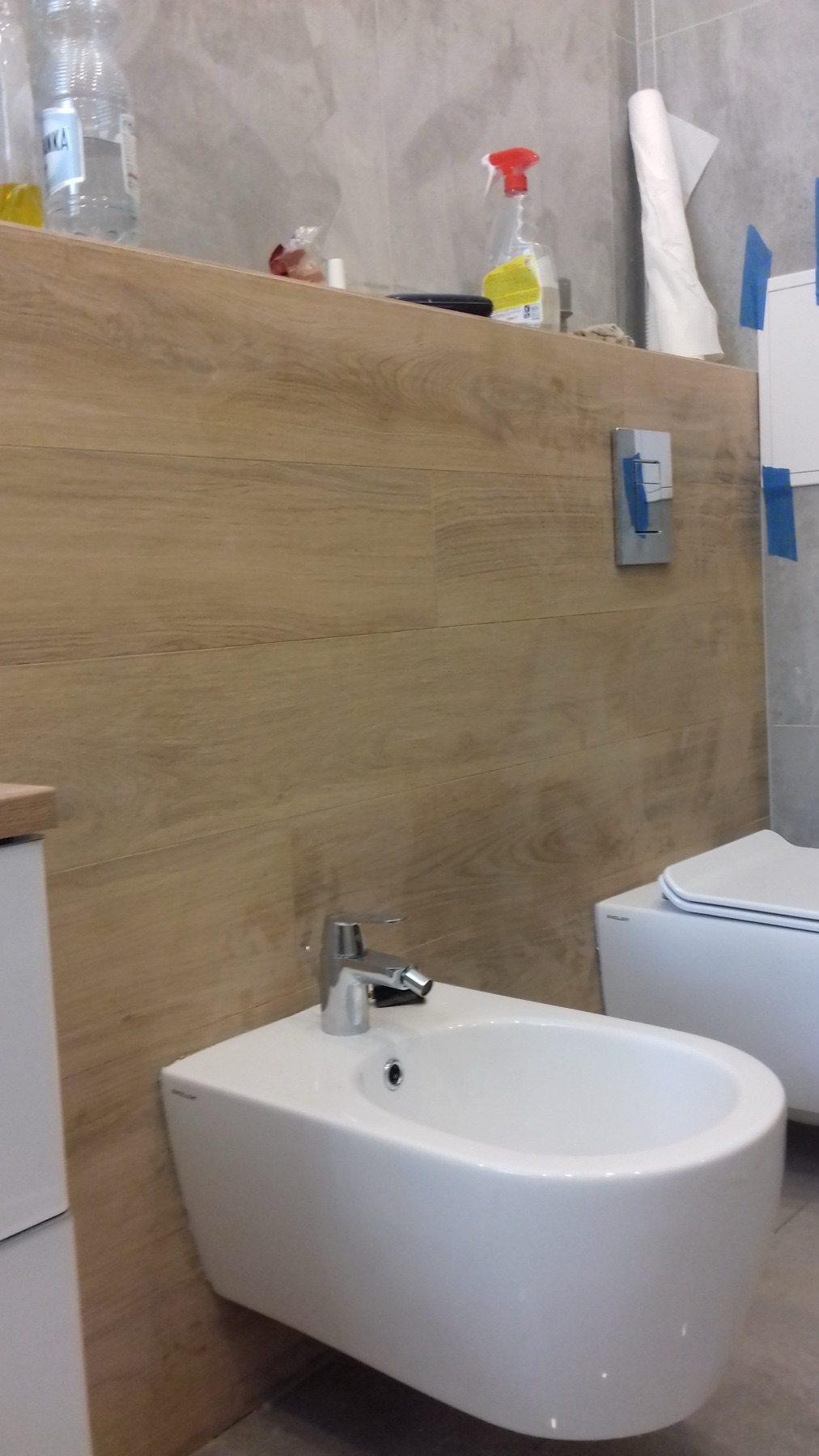 Bidet i fragment WC na tle płytek imitujących drewno